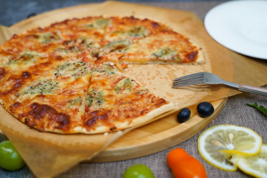 pexels-photo-27558296-27558296 A pizza with olives and tomatoes on a wooden cutting board