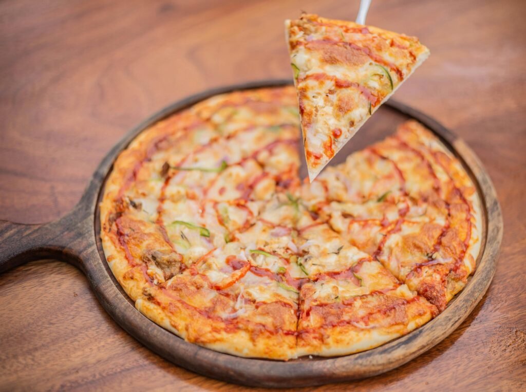 pexels-photo-27583268-27583268 A pizza with a slice missing from it on a wooden board