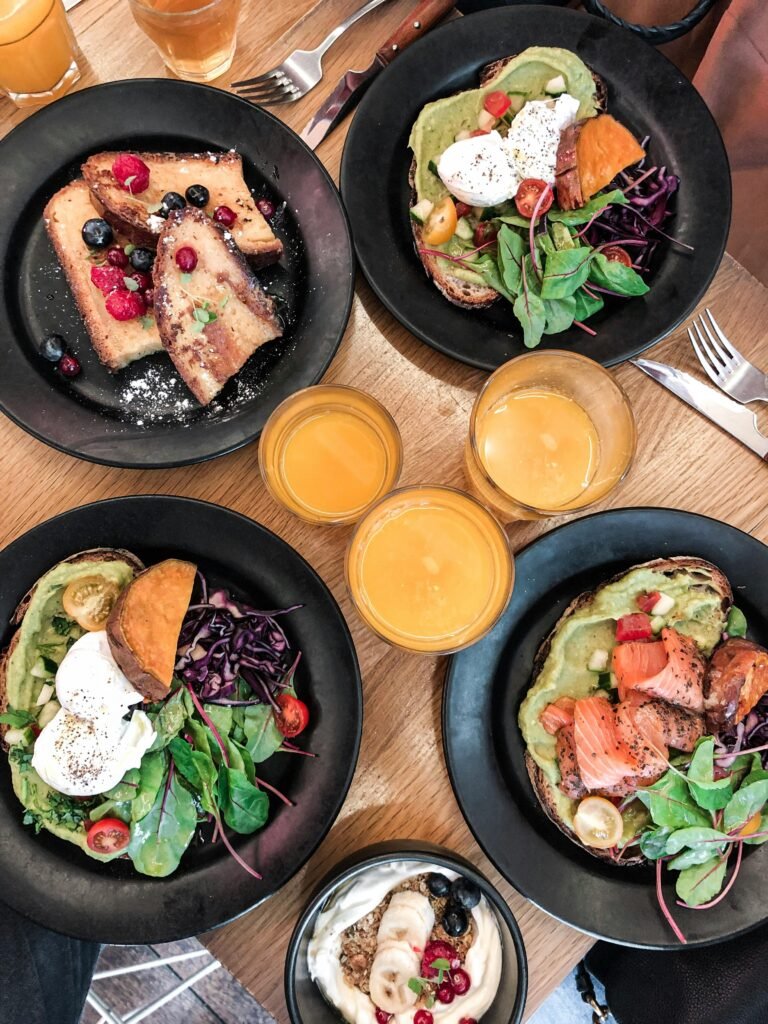 pexels-photo-2543270-2543270 Top-down view of a vibrant brunch spread featuring avocado toast, salmon, fresh salad, and juice.